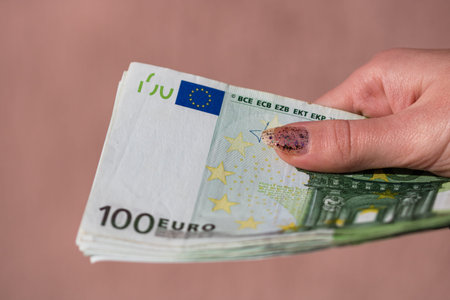 woman hands giving money like a bribe or tips. Holding EURO banknotes on a blurred background, EU...