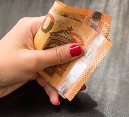 woman hands giving money like a bribe or tips. Holding EURO banknotes on a blurred background, EU currencyのeditorial素材
