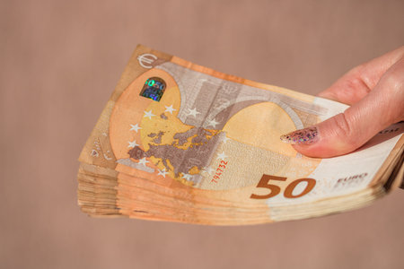 woman hands giving money like a bribe or tips. Holding EURO banknotes on a blurred background, EU...