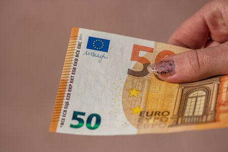 woman hands giving money like a bribe or tips. Holding EURO banknotes on a blurred background, EU currencyのeditorial素材