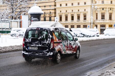 Snow on cars in the morning. Winter season and icy cars on the road in morning rush hour traffic of Bucharest, Romania, 2020のeditorial素材