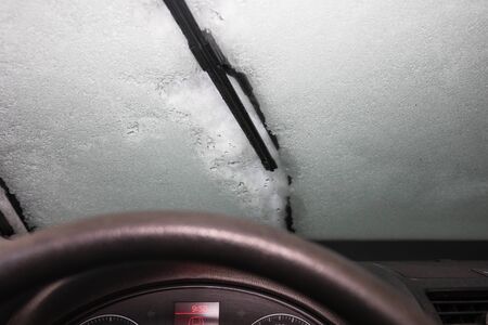 inside icy car, interior car dashboard close up. windshield wiper with snowの写真素材