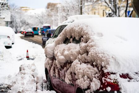 Cars covered with snow from the first snow fall of the year. Winter concept, snowy cars parked on the street, deep layer of snowの写真素材