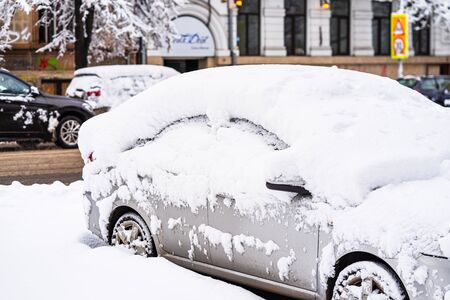 Cars covered with snow from the first snow fall of the year. Winter concept, snowy cars parked on the street, deep layer of snowの写真素材