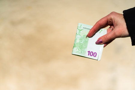 Woman hand holding and giving money. World money concept, close up of 100 EURO banknote, photo of...