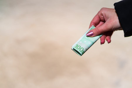 Woman hand holding and giving money. World money concept, close up of 100 EURO banknote, photo of...