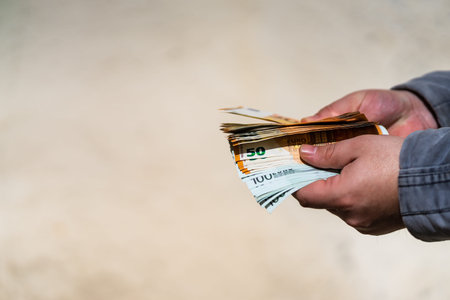 Man hand giving money like a bribe or tips. Holding EURO banknotes on a blurred background, EURO...
