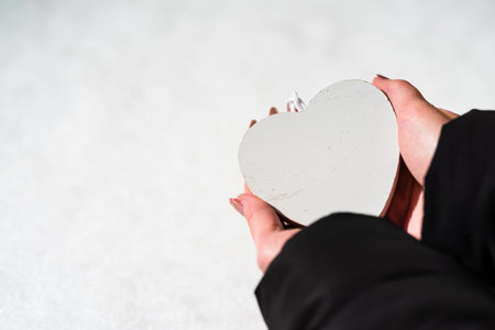 Woman hand holding a wooden heart with copy space. Valentineâs day concept, a symbol of loveの写真素材
