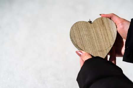 Woman hand holding a wooden heart with copy space. Valentineâ€™s day concept, a symbol of love
