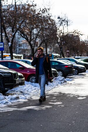 Young man holding a cell phone, mobile phone, walking while on the phone in Bucharest, Romania, 2020のeditorial素材