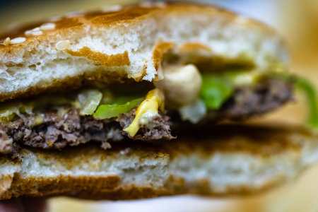 Close up detail of a bitten cheeseburger. Food, junk food and fast food conceptの写真素材