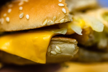Close up detail of a bitten cheeseburger. Food, junk food and fast food concept