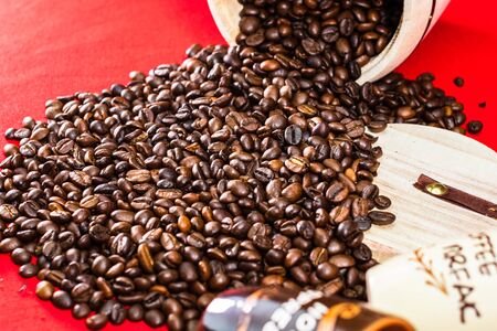 Cup of coffee, wooden coffee jar and roasted coffee beans in a sack on red background, top view, copy space for text, coffee conceptの写真素材