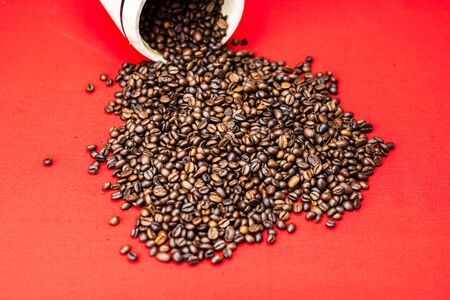 Roasted coffee beans in a wooden coffee jar on red background, top view, copy space for text, coffee conceptの写真素材