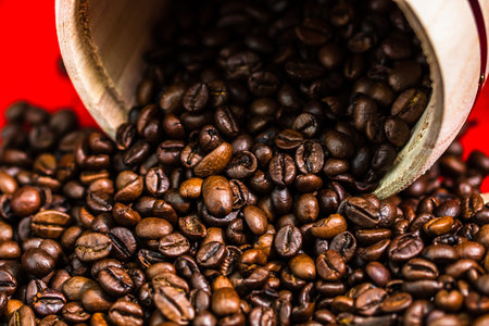 Roasted coffee beans in a wooden coffee jar on red background, top view, copy space for text, coffee conceptの写真素材