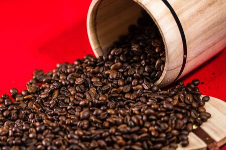 Roasted coffee beans in a wooden coffee jar on red background, coffee conceptの写真素材