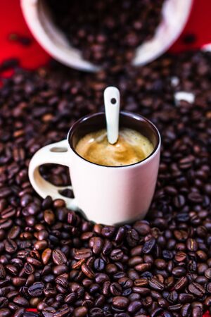 Close up of cup of coffee, roasted coffee beans on red background, coffee concept, close up coffee photoの写真素材