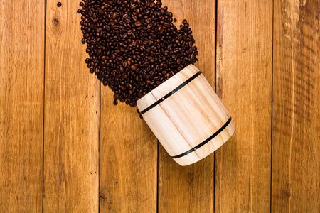 Coffee wooden barrel, roasted coffee beans on wooden background, coffee wooden jar top view, copy space for text, close up coffee photoの写真素材