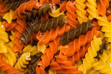 Composition of raw pasta uncooked tricolore fusilli, pasta twist shape. Close up and selective focus on colorful fusilli pasta.の写真素材