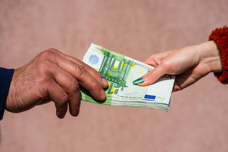 Hand giving money like bribe or tips or salary isolated, hard worked hand taking euro banknotes. Currency transfer and reward for hard work.の写真素材