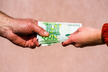 Hand giving money like bribe or tips or salary isolated, hard worked hand taking euro banknotes. Currency transfer and reward for hard work.の写真素材