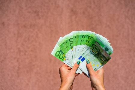 Hand holding and showing a fan of euro money or giving money. World money concept, 100 EURO...