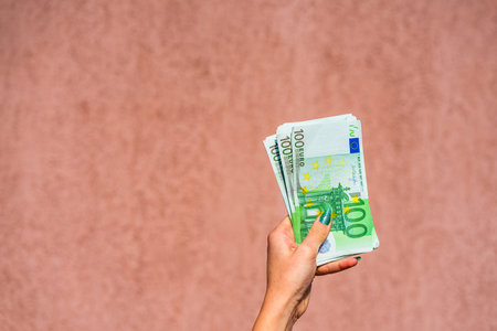 Hand holding and showing euro money or giving money. World money concept, 100 EURO banknotes EUR...