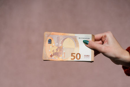 Hand holding showing euro money and giving or receiving money like tips, salary. 50 EURO banknotes...