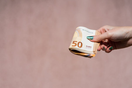 Hand holding showing euro money and giving or receiving money like tips, salary. 50 EURO banknotes EUR currency isolated. Concept of rich business people, saving or spending money.の写真素材