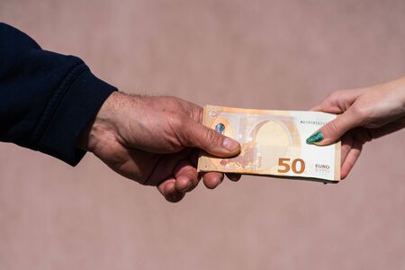 Hand giving money like bribe or tips or salary isolated, hard worked hand taking euro banknotes. Currency transfer and reward for hard work.の写真素材