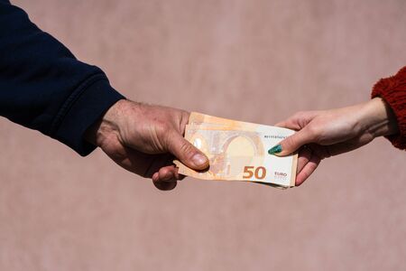 Hand giving money like bribe or tips or salary isolated, hard worked hand taking euro banknotes. Currency transfer and reward for hard work.の写真素材