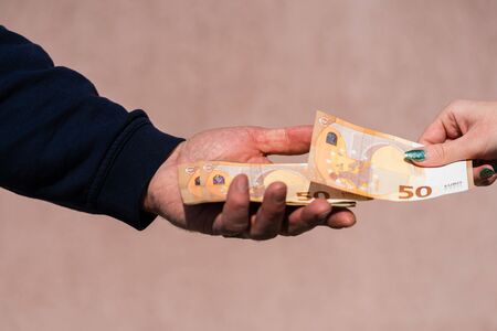Hand giving money like bribe or tips or salary isolated, hard worked hand taking euro banknotes. Currency transfer and reward for hard work.の写真素材