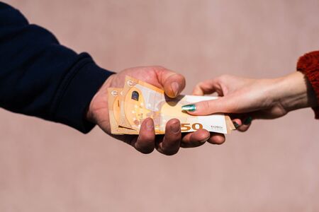 Hand giving money like bribe or tips or salary isolated, hard worked hand taking euro banknotes. Currency transfer and reward for hard work.の写真素材