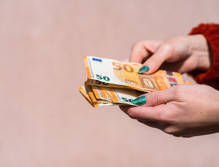 Hand holding showing euro money and giving or receiving money like tips, salary. 50 EURO banknotes EUR currency isolated. Concept of rich business people, saving or spending money.の写真素材
