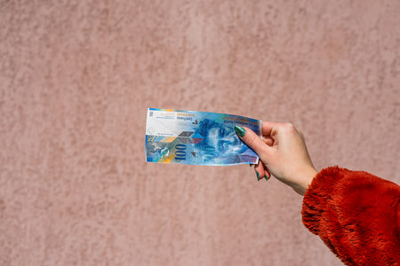 Hand holding showing euro money and giving or receiving money like tips, salary. 100 swiss franc...