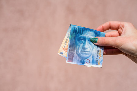 Hand holding showing euro money and giving or receiving money like tips, salary. 100 swiss franc...