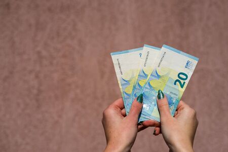 Hand holding showing euro money and giving or receiving money like tips, salary. 20 EURO banknotes EUR currency isolated. Concept of rich business people, saving or spending money.の写真素材