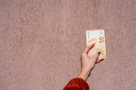 Hand holding showing euro money and giving or receiving money like tips, salary. 50 EURO banknotes...