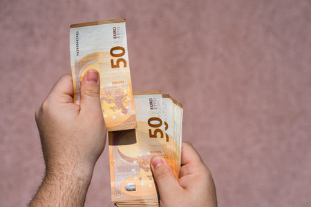 Hand holding showing euro money and giving or receiving money like tips, salary. 50 EURO banknotes...