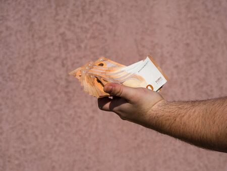 Hand holding showing euro money and giving or receiving money like tips, salary. 50 EURO banknotes EUR currency isolated. Concept of rich business people, saving or spending money.の写真素材