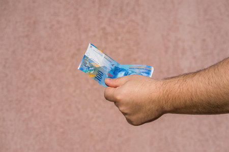 Hand holding showing euro money and giving or receiving money like tips, salary. 100 swiss franc...