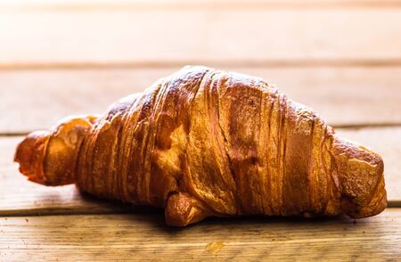 Detail of fresh croissant on wooden table. Food and breakfast concept. Top view and copy spaceの写真素材