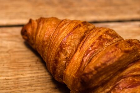 Detail of fresh croissant on wooden table. Food and breakfast concept. Top view and copy spaceの写真素材