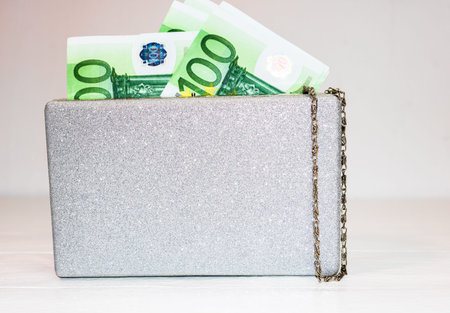 Glittery silver clutch bag with money isolated on white background with copy space.