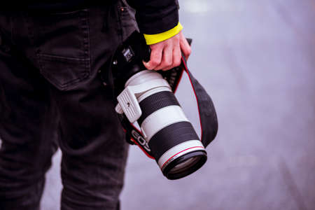 Street photographer holding a DSLR camera and telephoto lens on a rainy day in downtown Bucharest, Romania, 2020のeditorial素材
