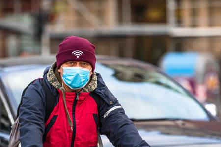 Covid-19 flu disease virus spreading in Europe. People wearing medical mask against coronavirus, influenza viruses and diseases. Healthcare concept. Man riding a bike wearing surgical mask on face in public spaces in Bucharest, Romania, 2020のeditorial素材