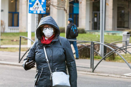 Covid-19 flu disease virus spreading in Europe. People wearing medical mask against coronavirus, influenza viruses and diseases. Healthcare concept. Woman wearing surgical mask on face in public spaces in Bucharest, Romania, 2020のeditorial素材