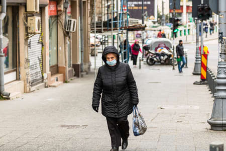 Covid-19 flu disease virus spreading in Europe. People wearing medical mask against coronavirus, influenza viruses and diseases. Healthcare concept. Woman wearing surgical mask on face in public spaces in Bucharest, Romania, 2020のeditorial素材