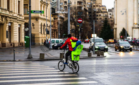 Man with kid on a bicycle crossing the street on a rainy day on the main boulevard of Bucharest city, Romania 2020のeditorial素材