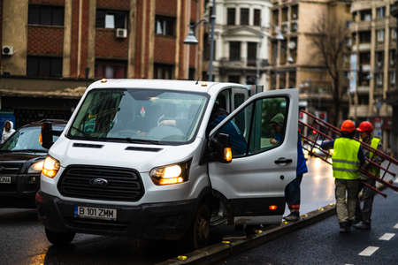 Workers unloading pieces of scaffold on a rainy day on the Victoriei boulevard in Bucharest city, Romania 2020のeditorial素材